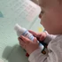 Baby hält eine Flasche natürlicher Baby-Bodylotion in der Hand – sanfte Pflege für empfindliche Babyhaut
